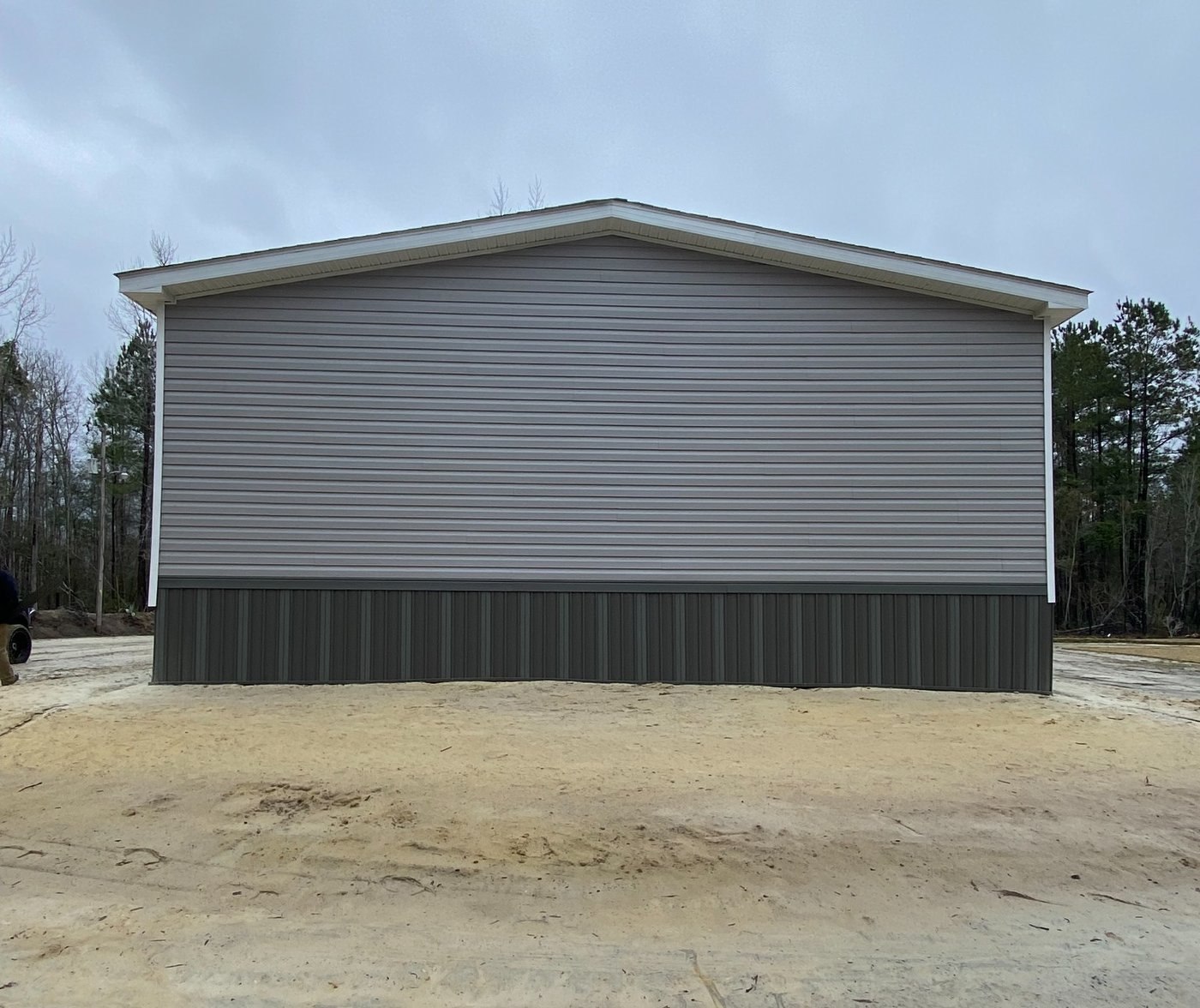 Manufactured-home gable end with gray siding and dark skirting.