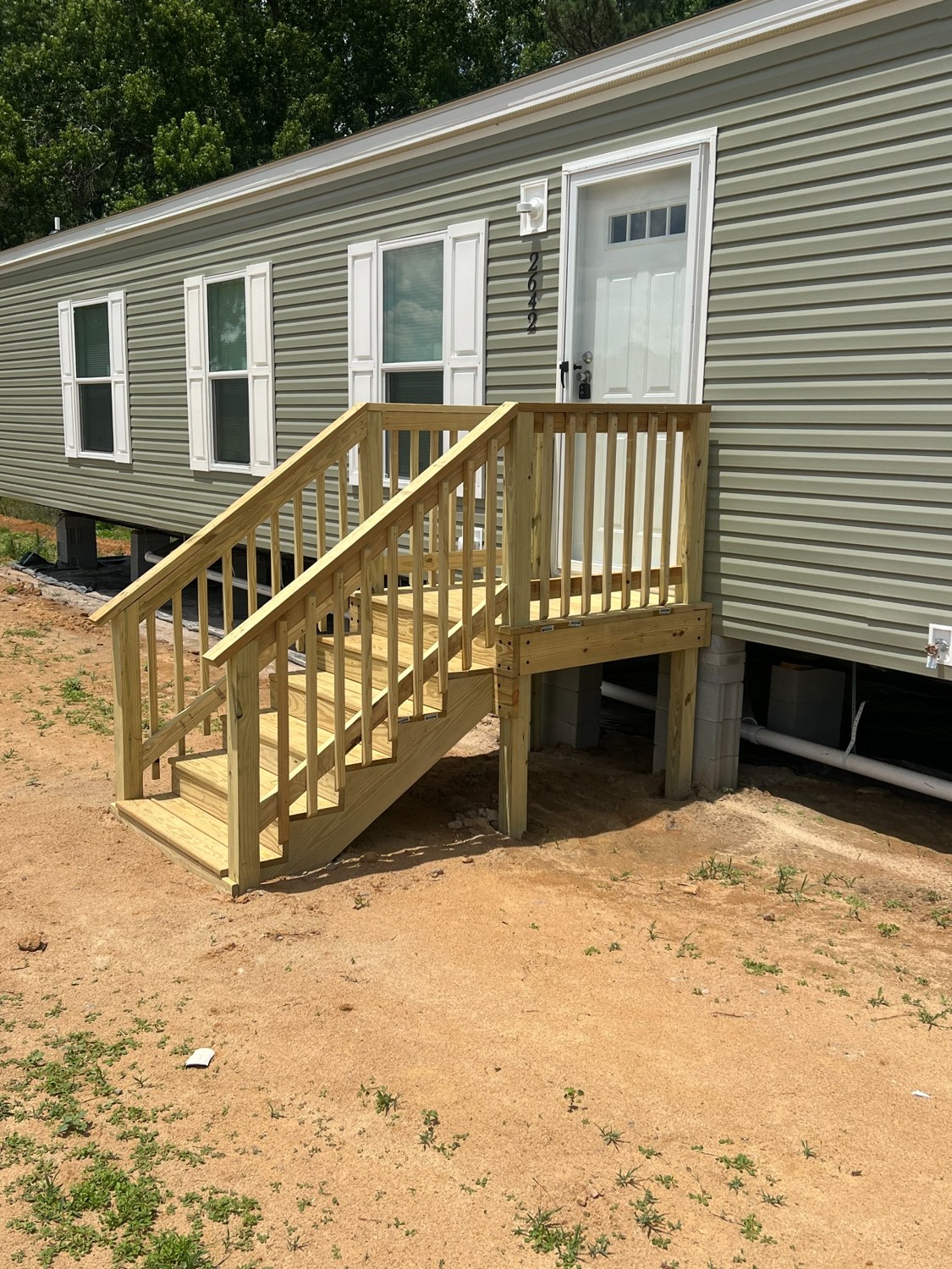 Wood porch landing and staircase with railings at a manufactured home.